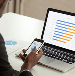 person-looking-at-data-on-phone-and-computer