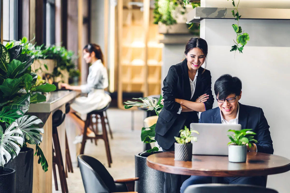 a business woman and man smiling while looking at a computer.